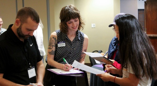 Photo of Quinlan Carttar and Summitt participants in conversation and writing