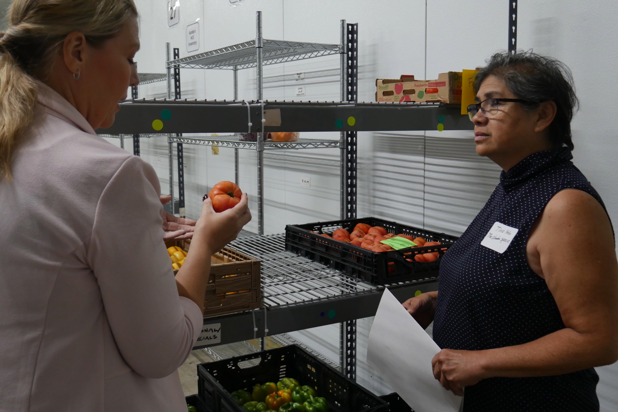 two people next to tomatoes