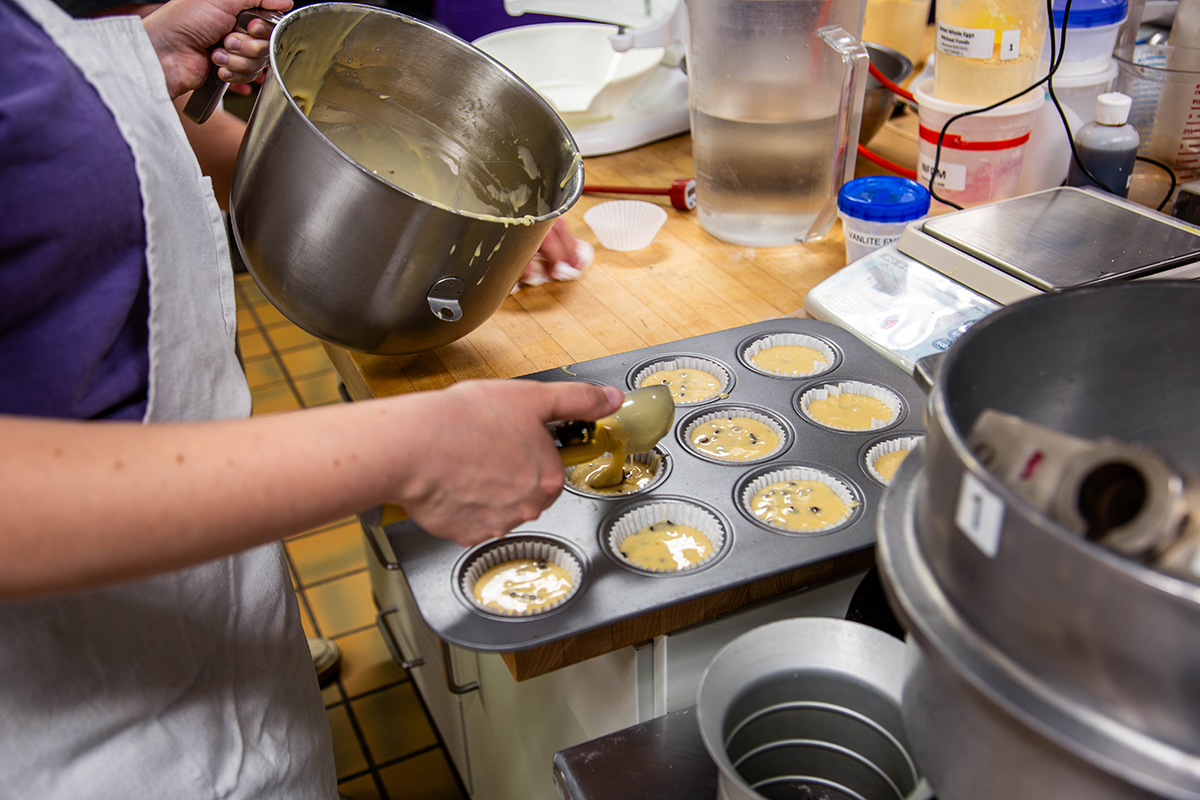 scooping muffin mix into tin