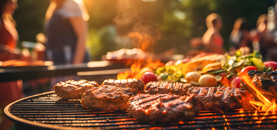 Closeup of barbecue grill, hamburgers and vegetables cooking