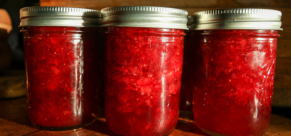 View of a row of glass jars filled with strawberry jelly View of a row of glass jars filled with strawberry jelly