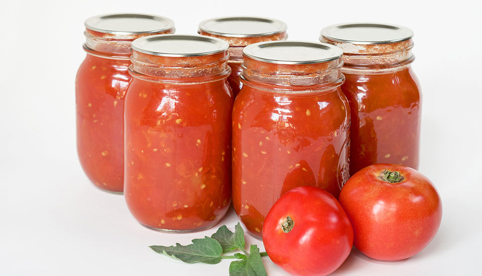 five jars of canned tomato sauce on a bright white background