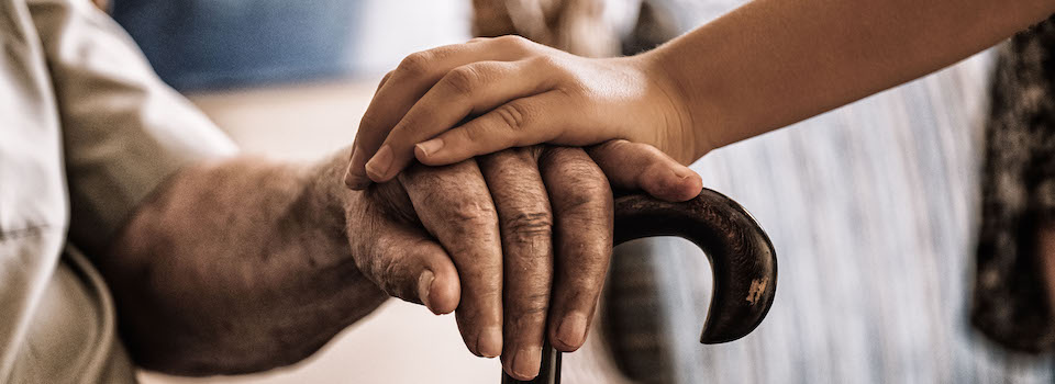 A grandmother and her granddaughter, holding onto a cane together.
