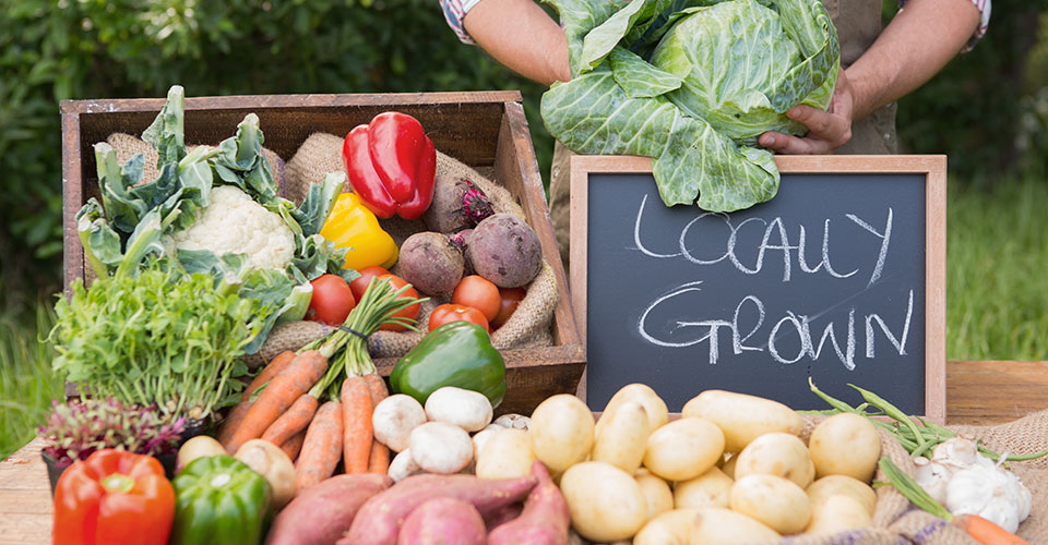 rural farm stand with a chalkboard signn that reads 'Locally Grown'