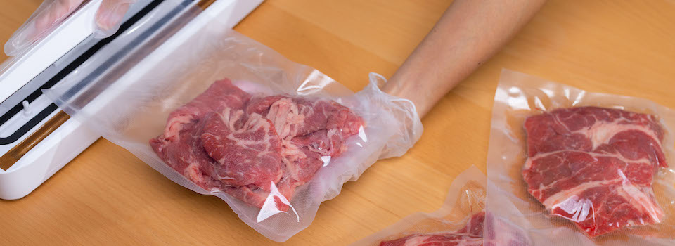 A woman vacuum sealing meat.