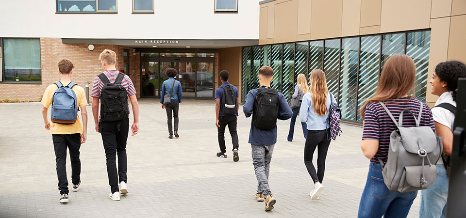 Small crowd of high school students walking into school Small crowd of high school students walking into school