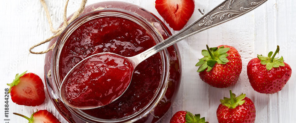 Top view, jar of strawberry jam with spoon sitting on top Top view, jar of strawberry jam with spoon sitting on top