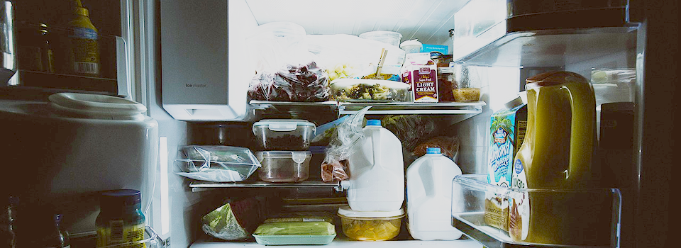 Refrigerator door open with light on in a dark room