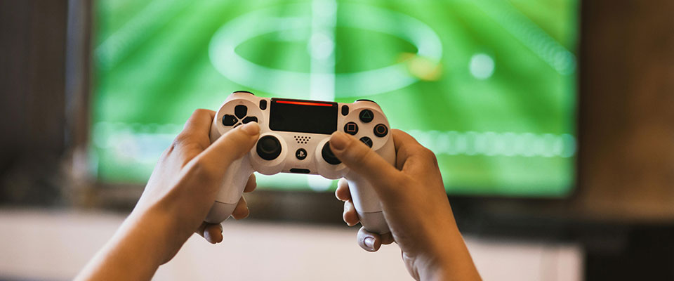 Closeup of hands with game controller, tv in background