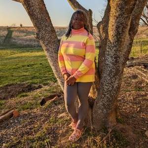 Dawn Alexander Halla, standing next to tree