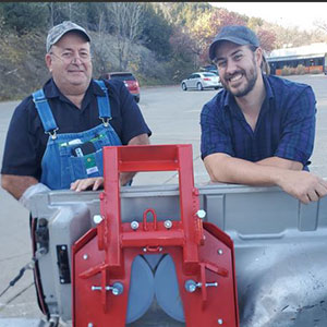 Kelly and Kyle Coover, standing next to tree chopping equipment