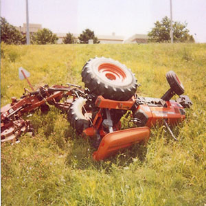 red tractor overturned on a grassy side hill