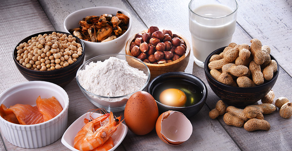 nine bowls or glasses sitting on table containing one of nine food allergens