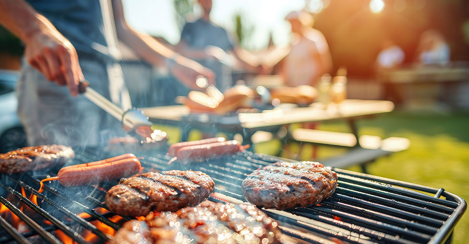 hot dogs and hamburgers cooking on an outdoor barbecue grill