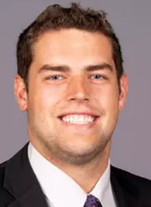 young man wearing black suit smiling at camera
