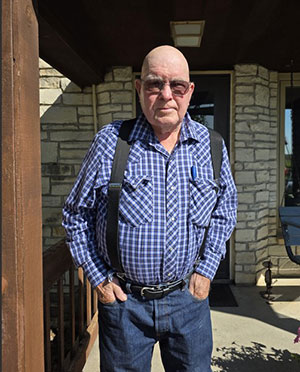 Man wearing blue jeans, checkered shirt and suspenders