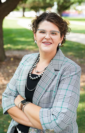 Woman with black hair and eyeglasses in checkered suit