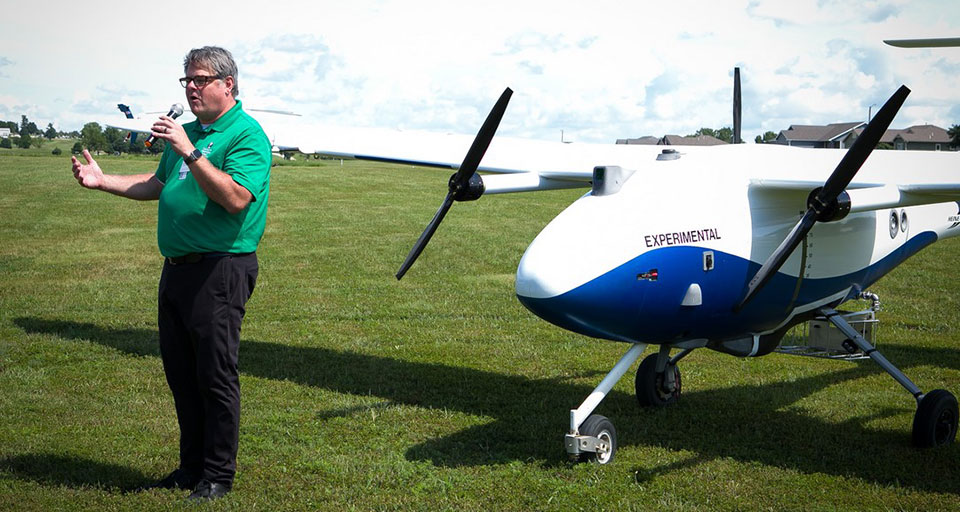 Man talking into microphone standing in front of large drone