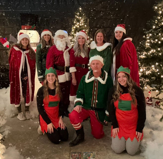 Several people dressed as Christmas elves with snow falling around them Several people dressed as Christmas elves with snow falling around them