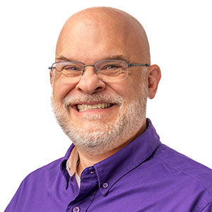 Portrait of man smiling at camera wearing eyeglasses and a purple shirt