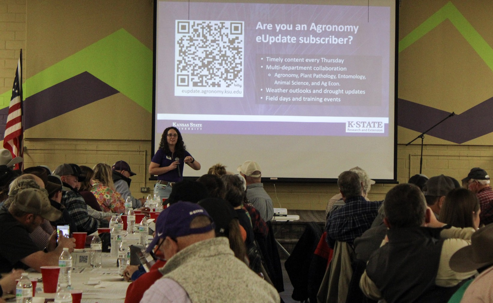 Woman presenting to audience in front of large white screen