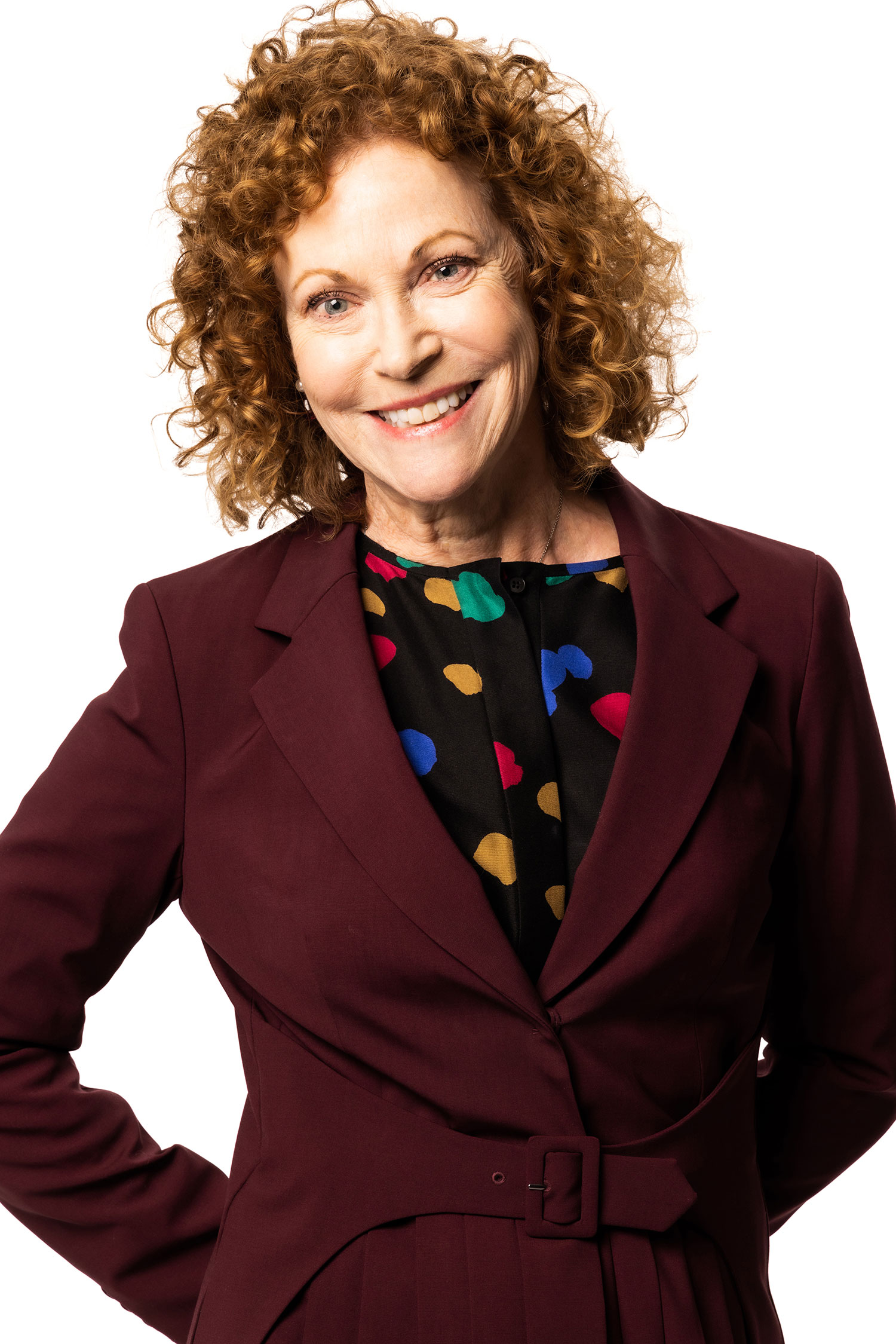Woman with red hair wearing a burgundy business suit and smiling at the camera