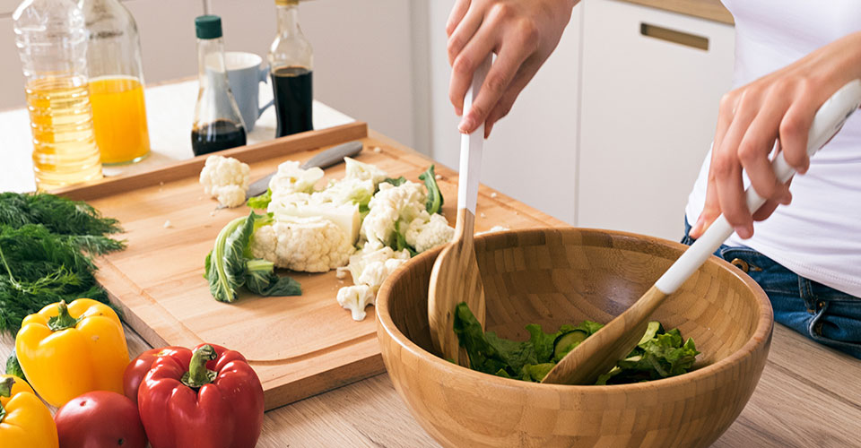 Hands mixing a salad at home. 