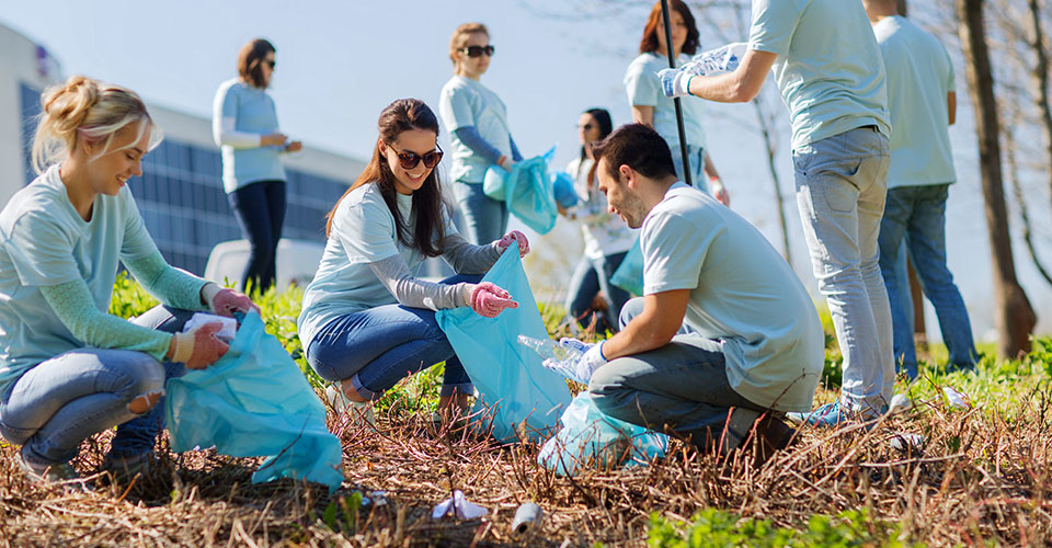 group of men and women putting trash into plastic bags
