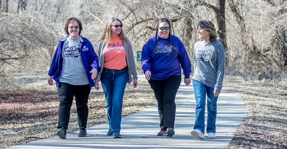 Four women walking down paved trail