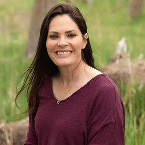 Portrait of woman with long dark hair wearing burgundy sweater smiling at camera