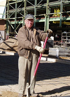 Man wearing a ball cap holding a shovel inside a warehouse yard
