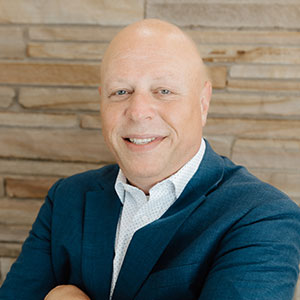Portrait of a man wearing a blue suit smiling at the camera