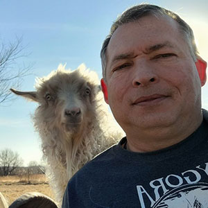Selfie taken by man with dark shirt and llama looking over his shoulder