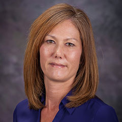 Portrait of woman with shoulder length brown hair wearing a blue shirt